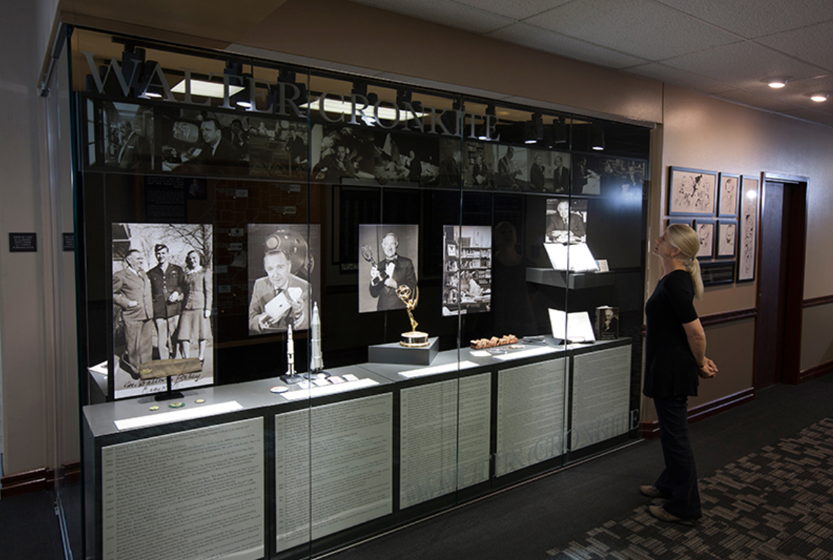 Memorial exhibit displays showcasing a Walter Cronkite museum exhibit case with interpretive graphics, historical artifacts, photographs, and memorabilia documenting his life and journalism career.