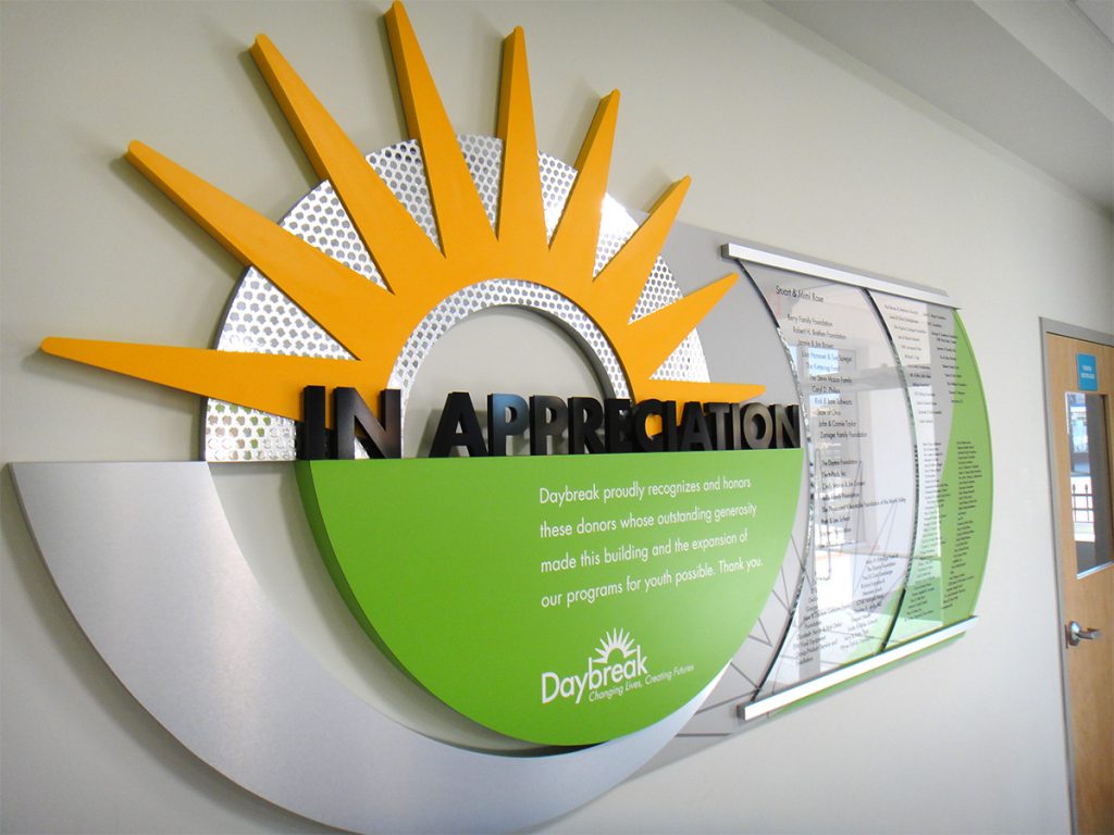 Daybreak capital campaign donor recognition display with dimensional sun rays, permanent donor panels, and integrated organizational branding.