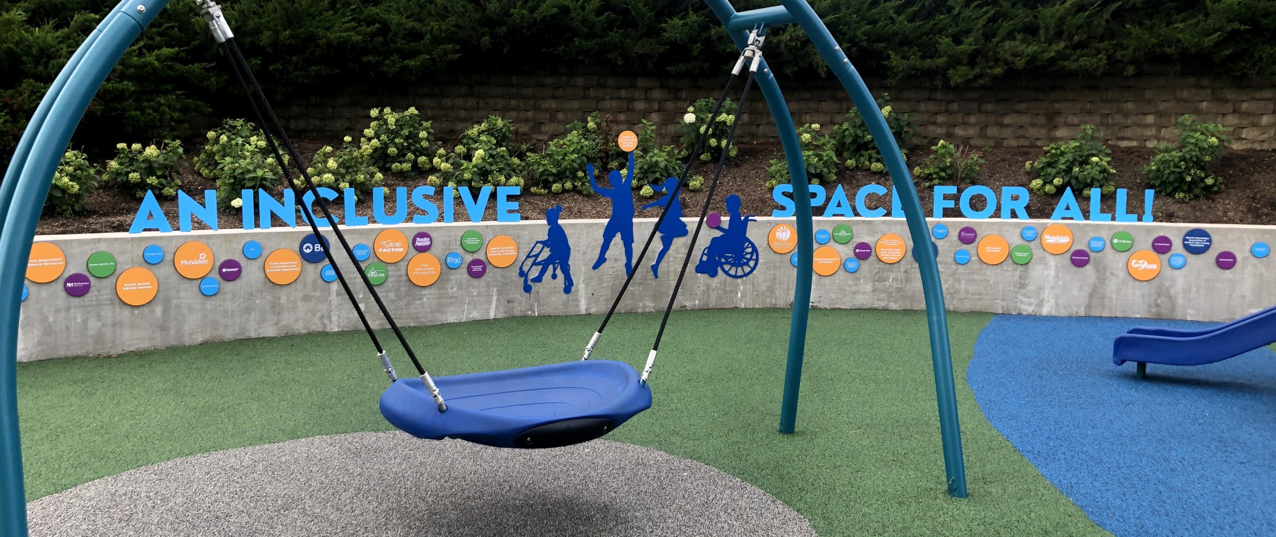 Colorful recognition wall with aqua letters “An Inclusive Space for All” and silhouettes of children, including mobility devices.