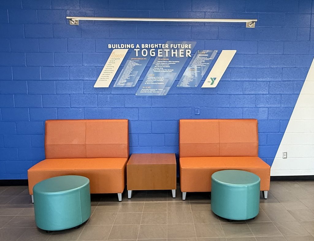 Close-up of the Clear Change donor display showing etched acrylic panels and silver standoffs.