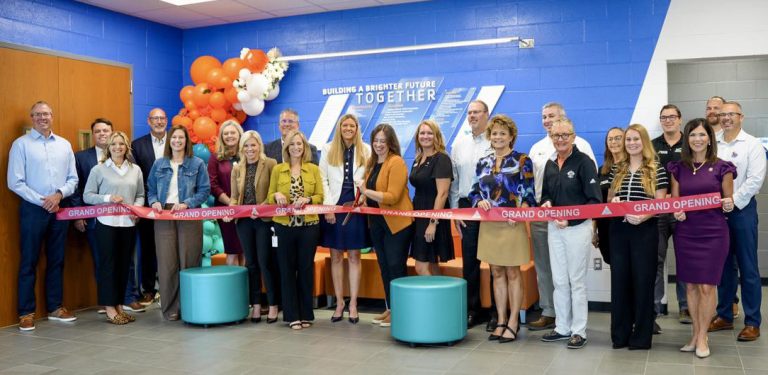 YMCA ribbon cutting event with new donor display visible in the background.