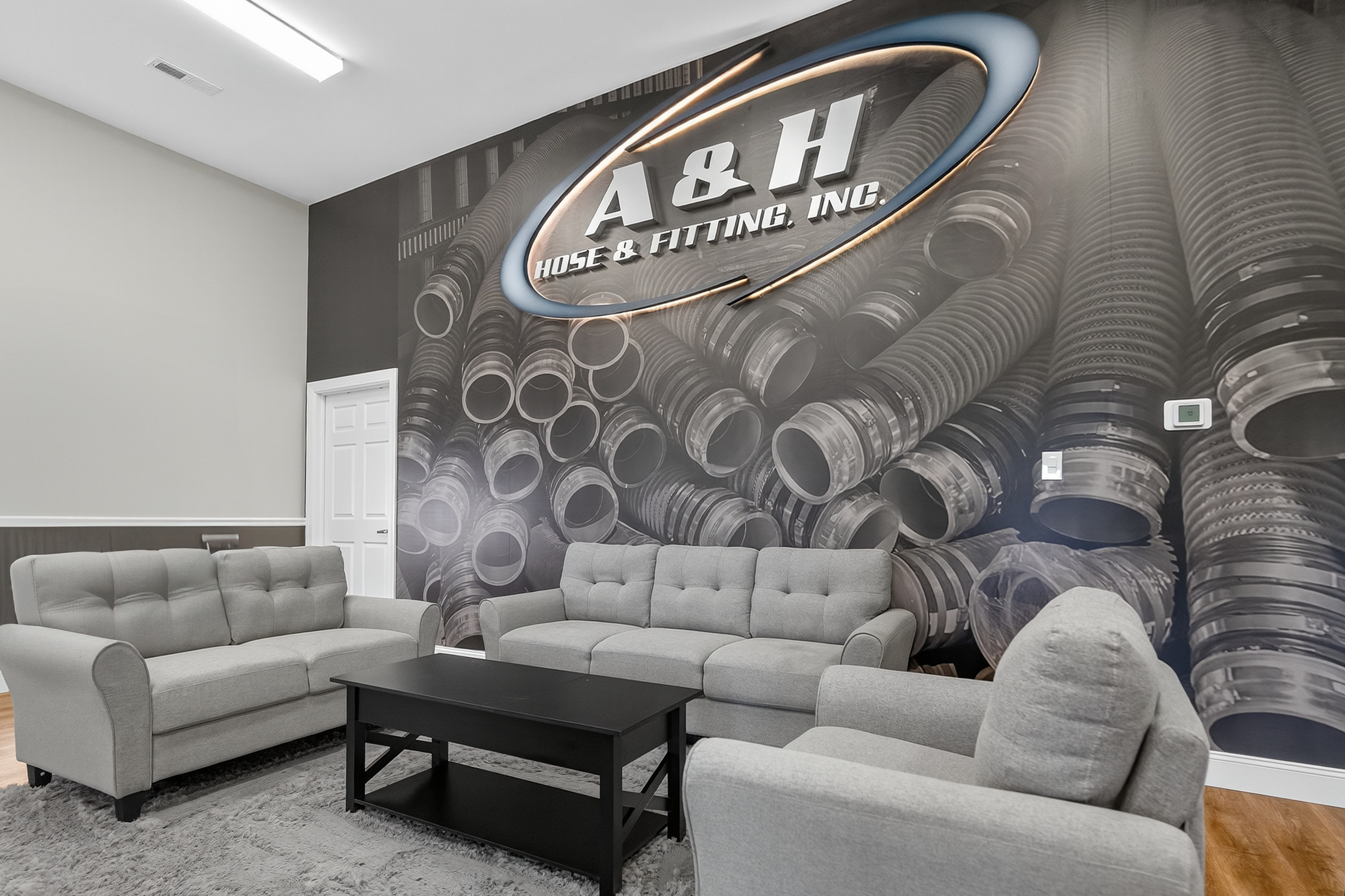 Custom wallpaper with dimensional, lit logo signage is an impactful, experiential design piece in A & H Hose's new lobby.