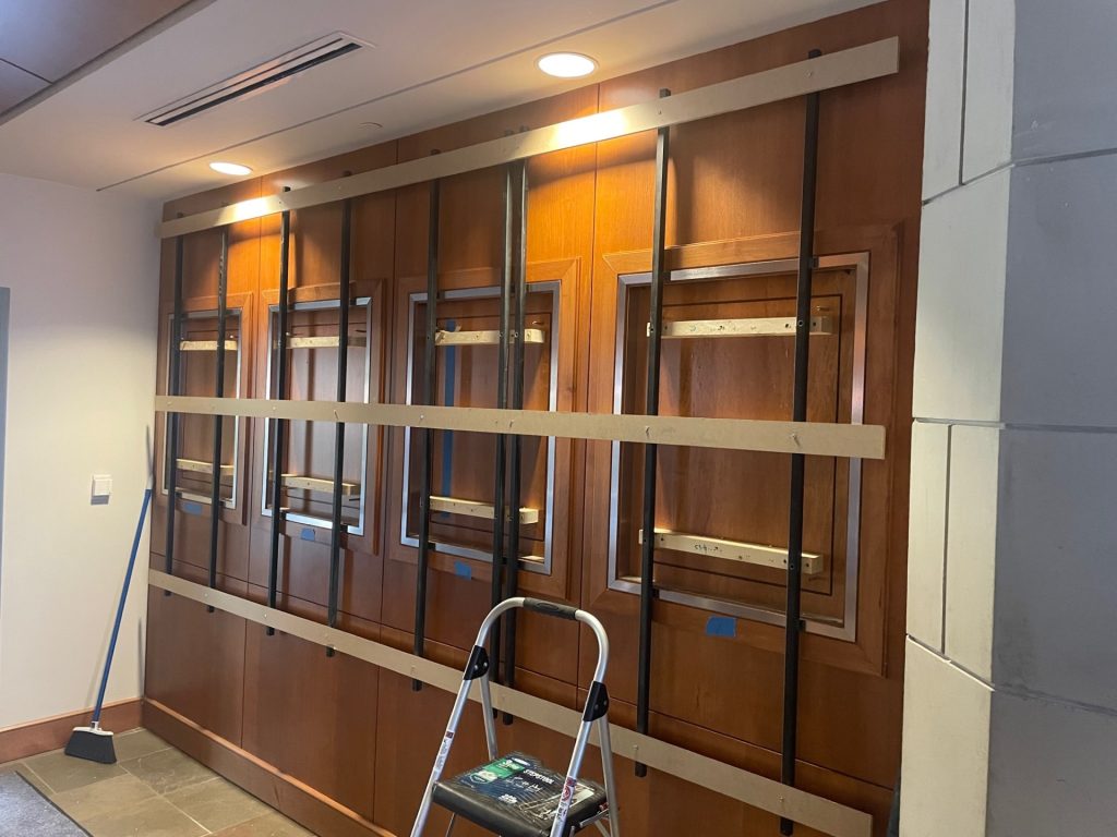 Structural support system for large university award display mounted without drilling into finished wood wall.