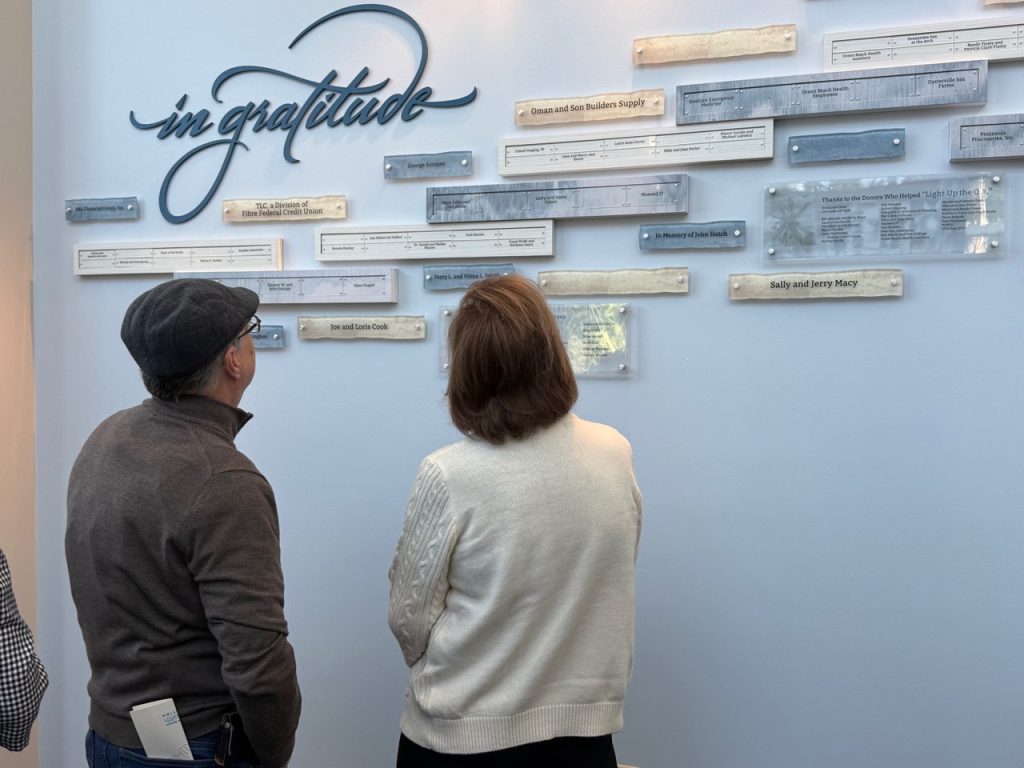 Donors take an up-close look at the cumulative giving donor recognition display in the hospital lobby.