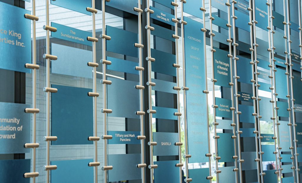 Detailed view of donor recognition wall system with vertical rods, layered panels, and integrated lighting for enhanced readability