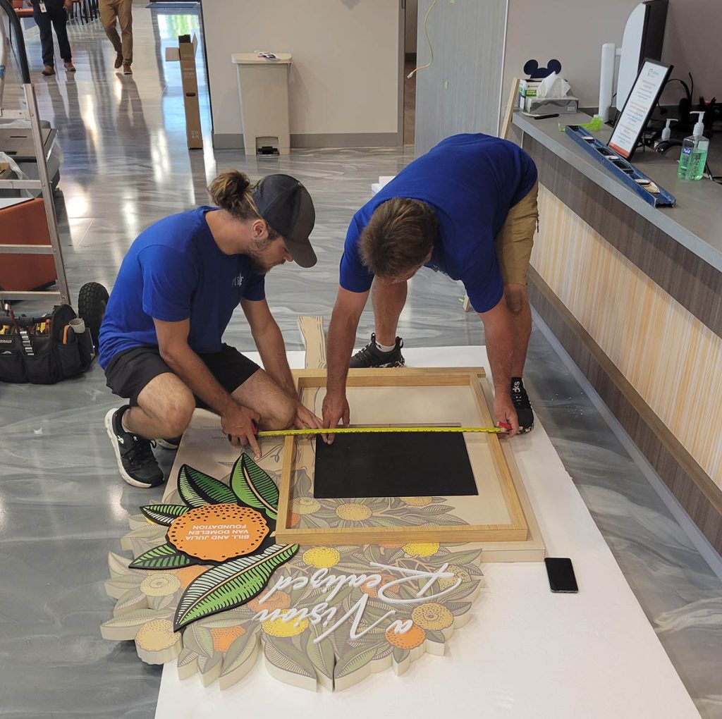PIR installation team preparing healthcare donor recognition wall components on site