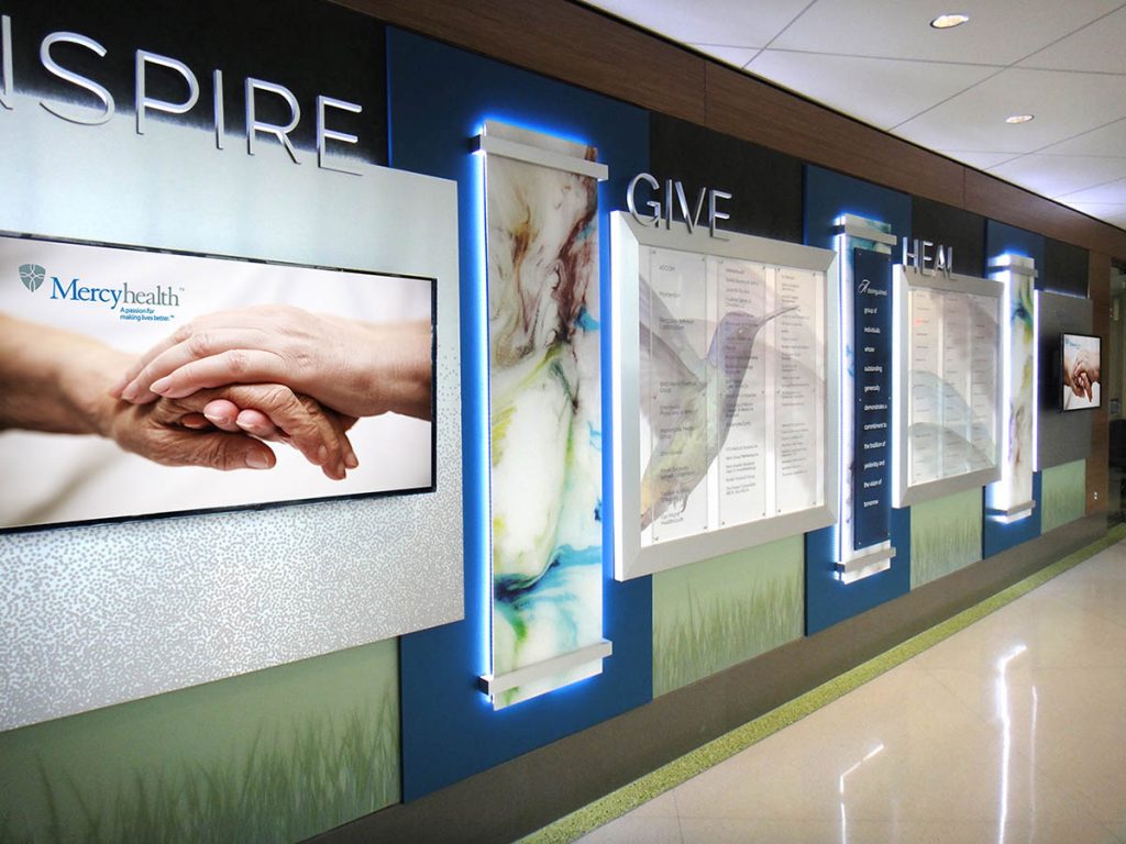 Healthcare donor recognition wall featuring illuminated donor panels, dimensional graphics, and integrated branding elements.