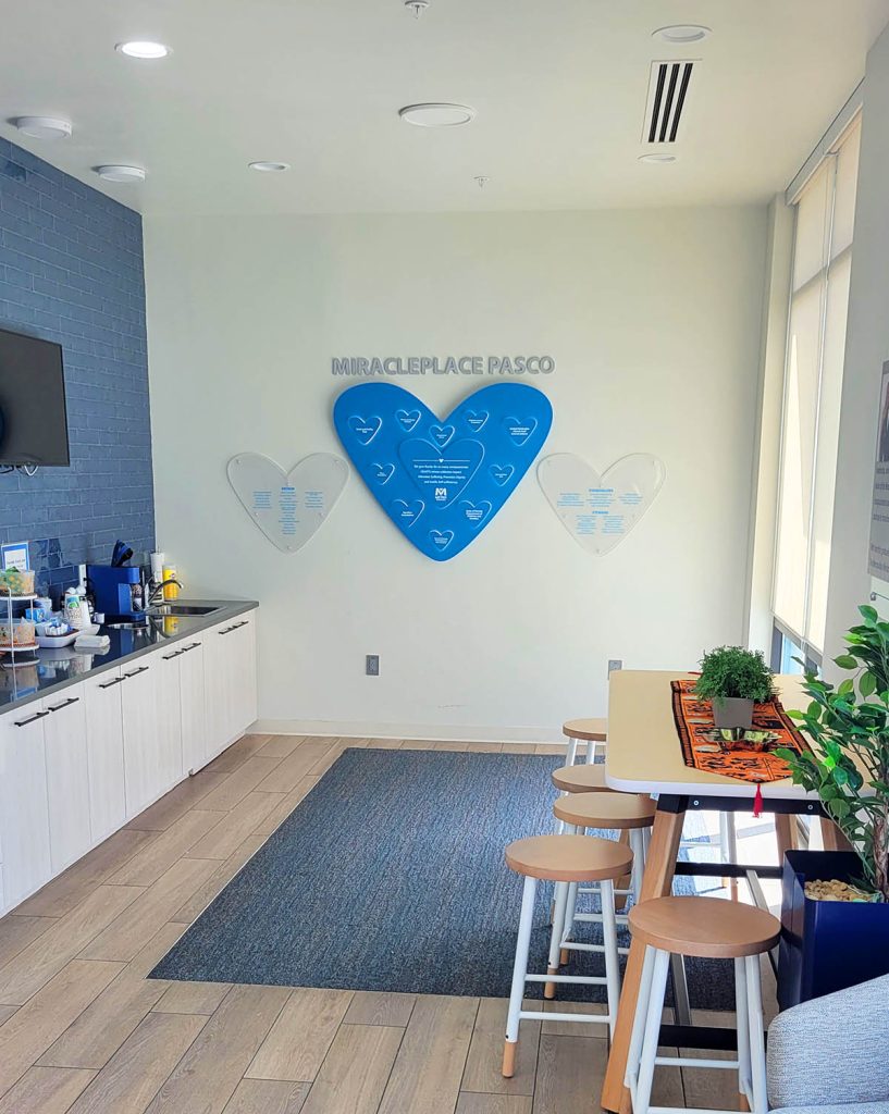 Faith based donor recognition display installed at Metropolitan Ministries featuring Ember Glow™ illuminated heart donor plaques and Clear Change™ recognition panels in a welcoming gathering space.