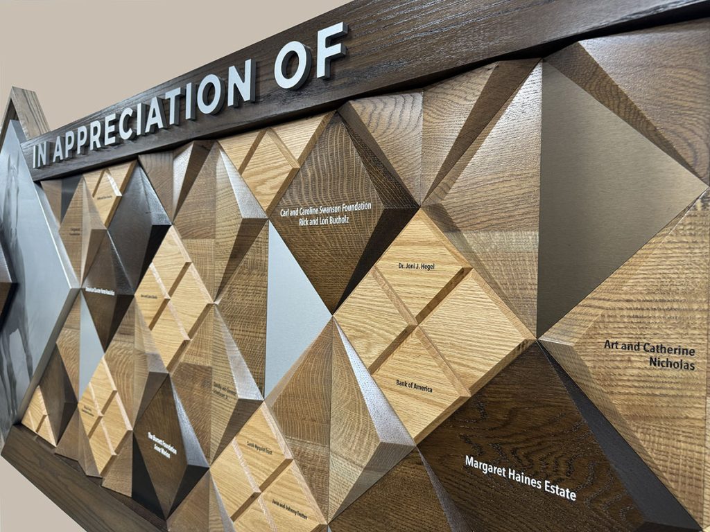 Close-up of dimensional wood and metal nameplates on the American Quarter Horse Foundation donor recognition wall.