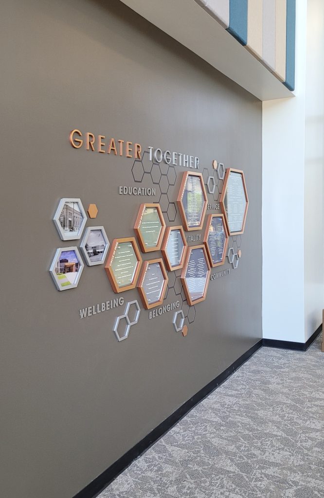 Left view of the Greater Midland community center donor recognition display featuring hexagonal donor panels, dimensional lettering, and the Clear Change System.