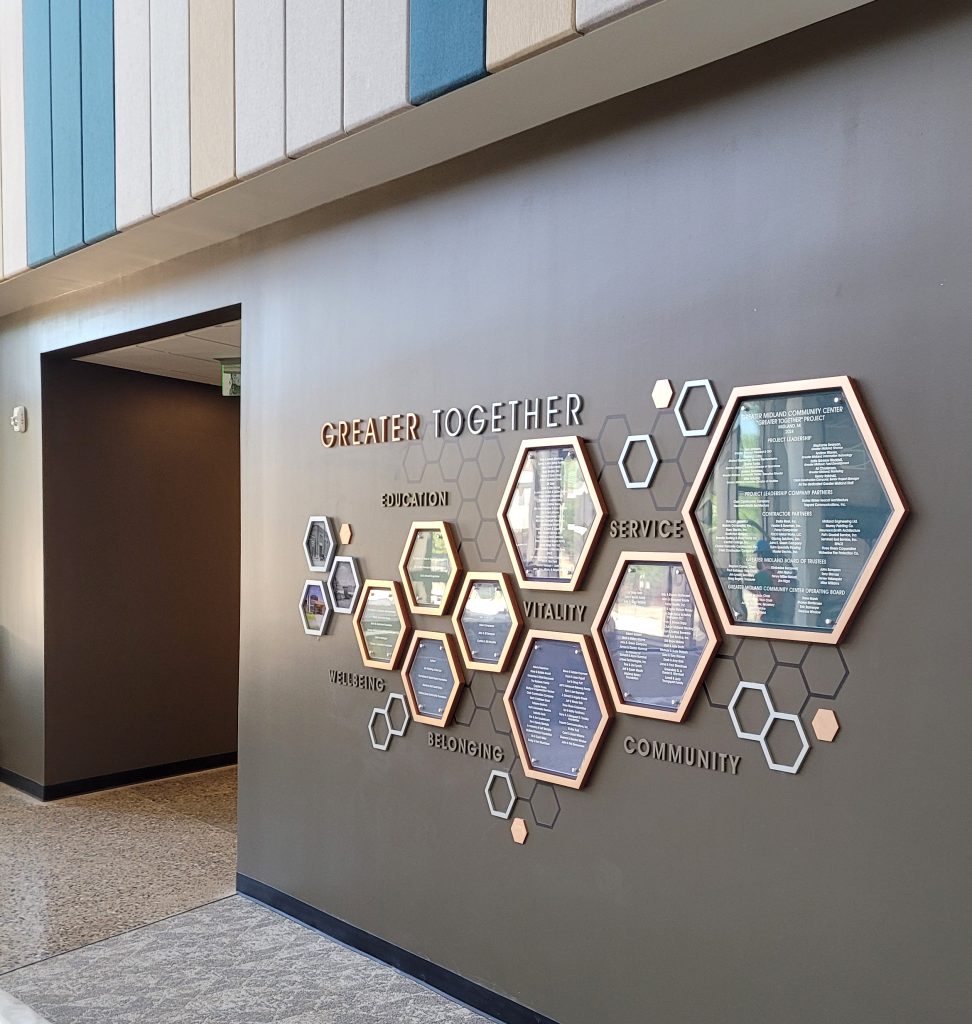 Right view of the Greater Midland community center donor recognition display featuring hexagonal donor panels and the Clear Change System.